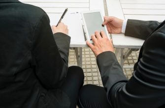 close up businessman businesswoman holding smart phone writing paper outdoors